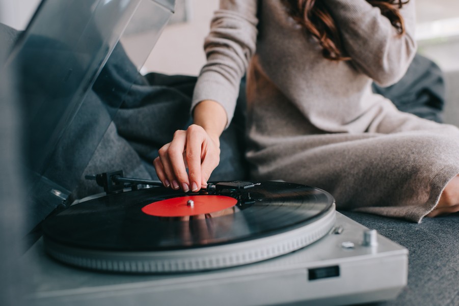 Woman placing a turntable needle on a vinyl record.  