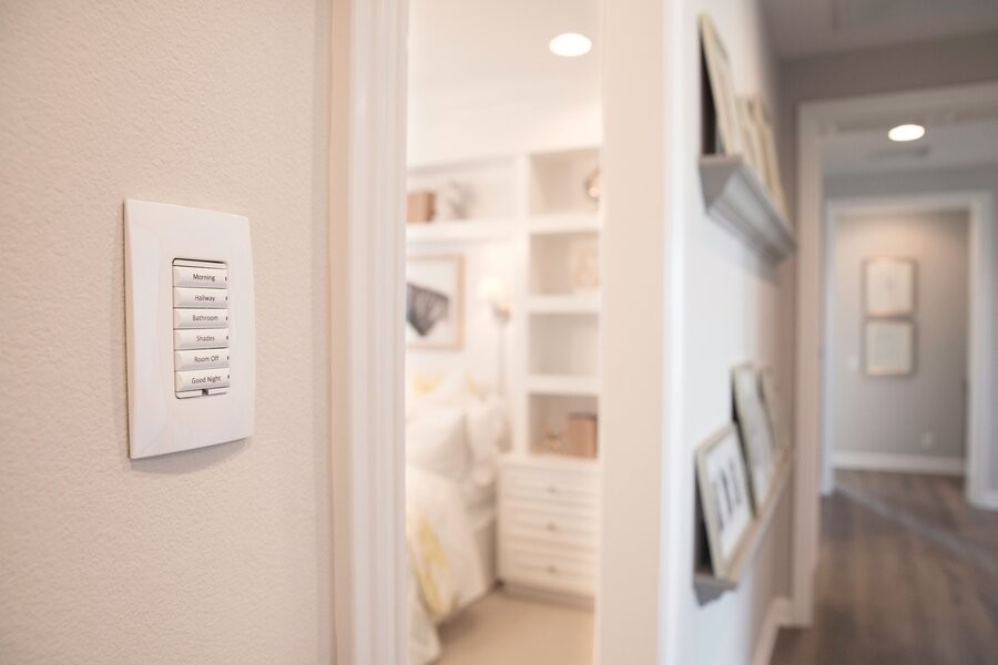 A hallway featuring a Control4 wall keypad illuminated by its lighting control system.