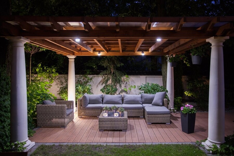 A backyard setup featuring comfy seating and outdoor and landscape lighting fixtures.